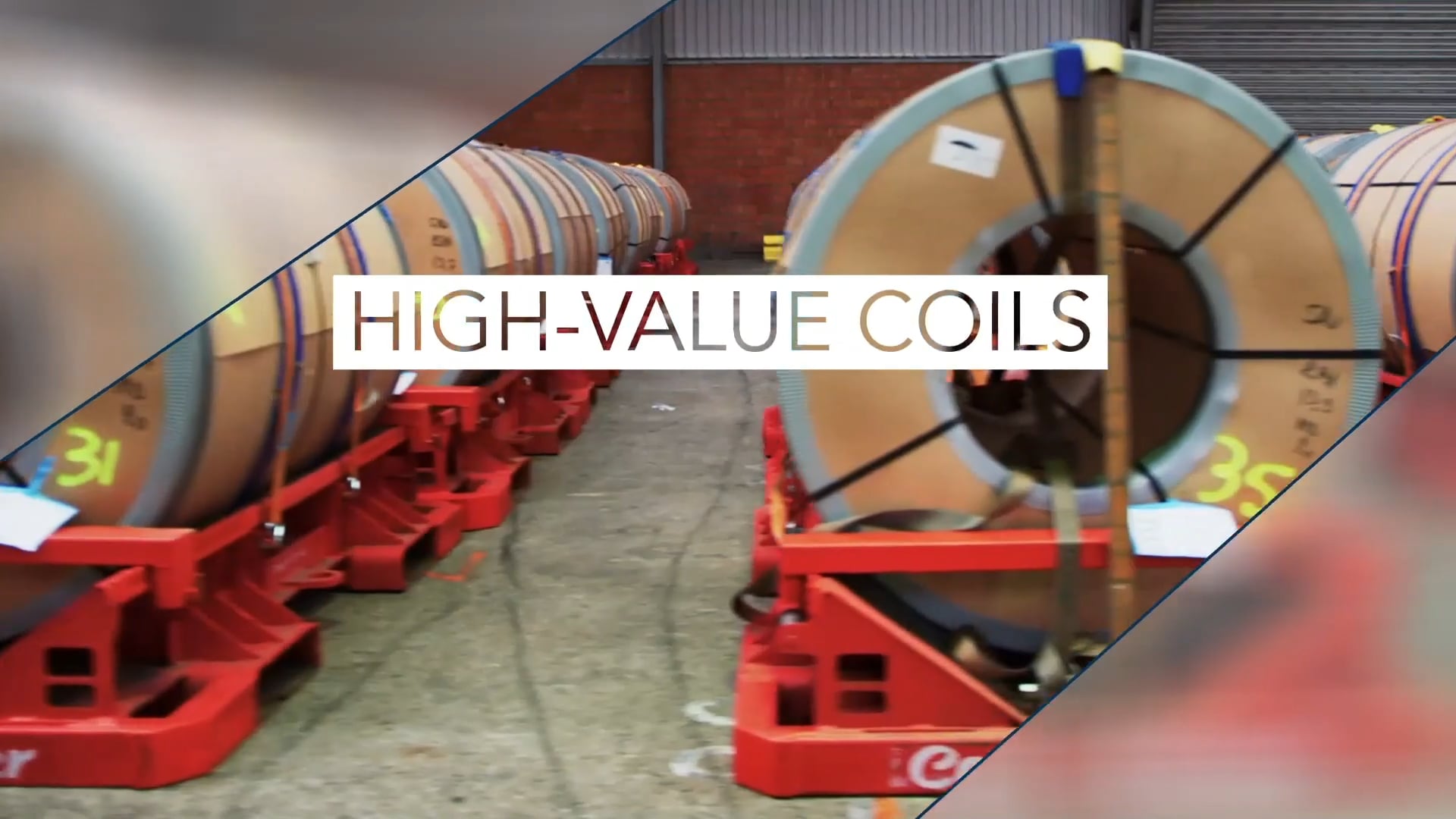 Steel coils secured on red Coil-Tainer pallets in a warehouse aisle